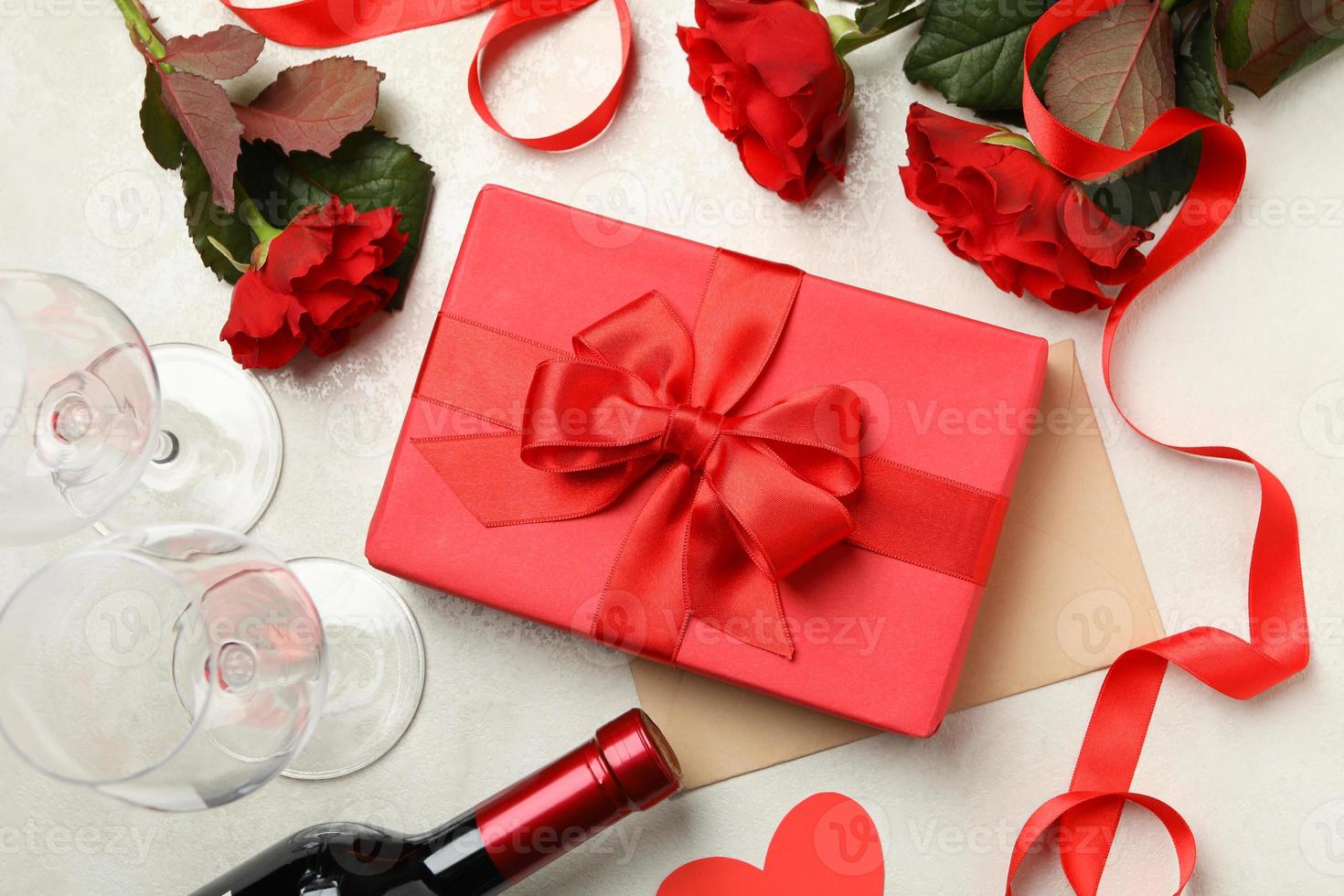 Konzept des Valentinstags mit Rosen, Wein und Geschenkbox auf weißem strukturiertem Hintergrund foto