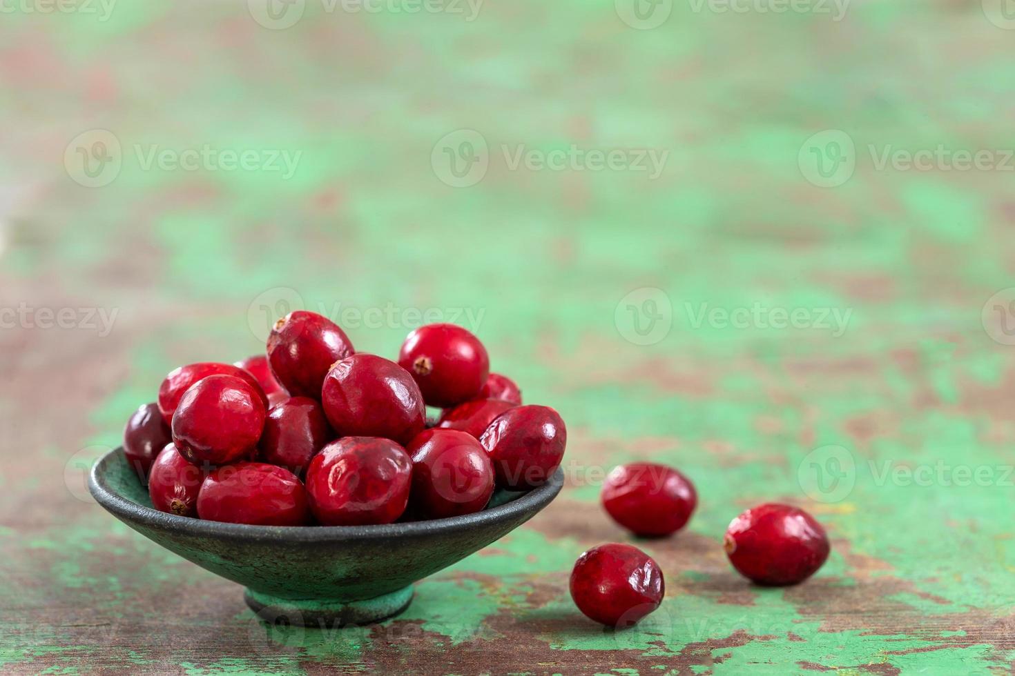 frische Cranberries Früchte in rustikaler asiatischer Schüssel auf altem grünem Holzhintergrund und Tageslicht foto