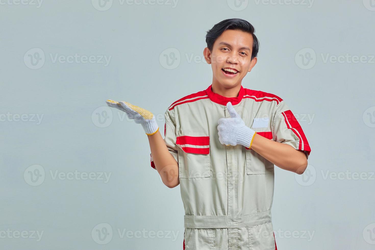 gut aussehender Mann in mechanischer Uniform, der eine gute Geste mit Daumen auf grauem Hintergrund macht foto