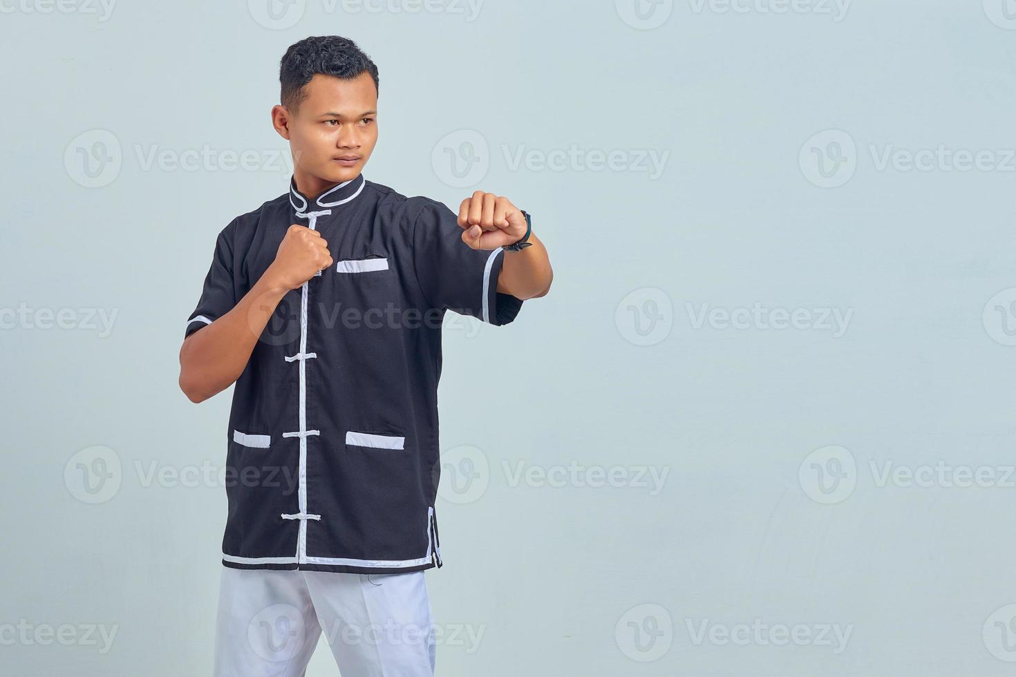 Porträt eines gutaussehenden asiatischen Sportlers mit Kimono, der Karate übt, isoliert auf grauem Hintergrund foto