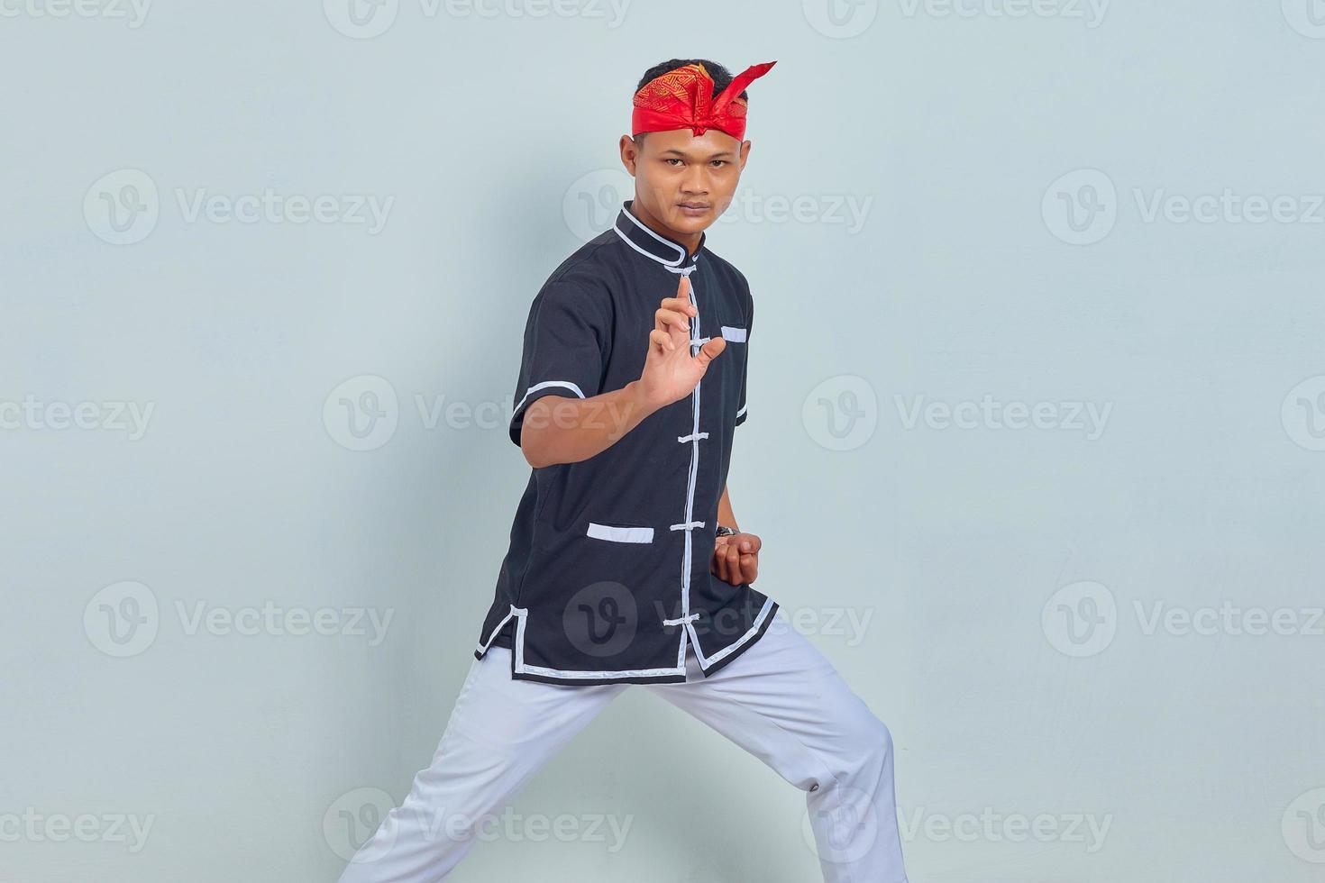 Bild des jungen Sportlers in Kimono-Praxis im Karate gekleidet auf grauem Hintergrund isoliert. Blick in die Kamera foto
