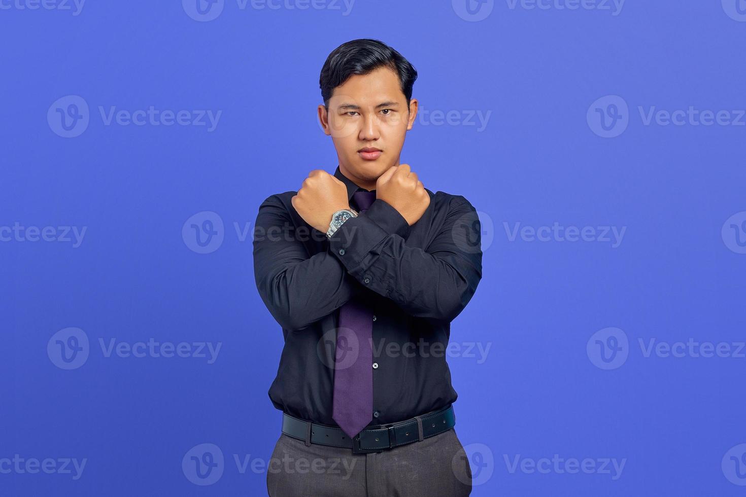 ernster junger gutaussehender geschäftsmann kreuzte hand und zeigt ablehnende geste auf violettem hintergrund foto