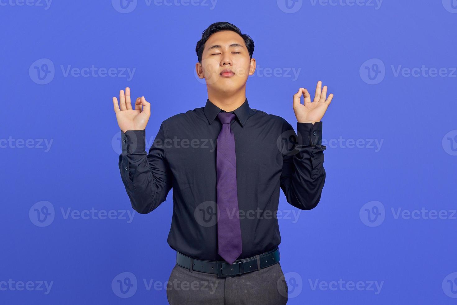 Foto eines gutaussehenden Geschäftsmannes schloss die Augen und machte Meditationsgesten mit den Fingern auf violettem Hintergrund