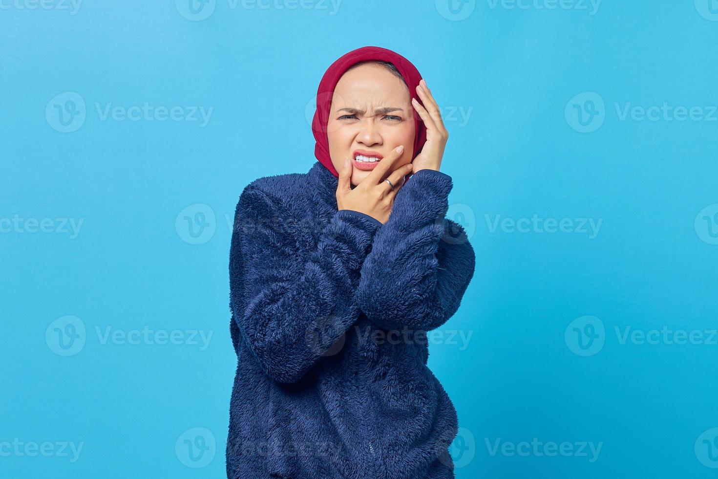 Porträt der schönen asiatischen Frau mit Zahnschmerzen mit Schmerzausdruck auf blauem Hintergrund foto