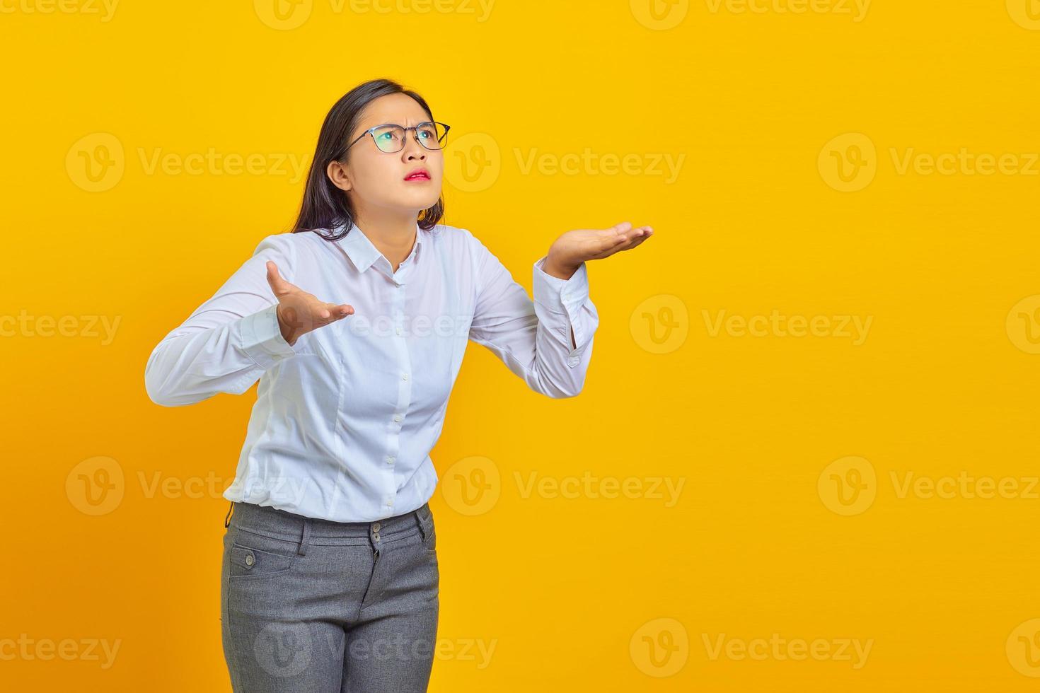 Foto einer schockierten jungen Geschäftsfrau mit verwirrtem und unzufriedenem Ausdruck auf gelbem Hintergrund