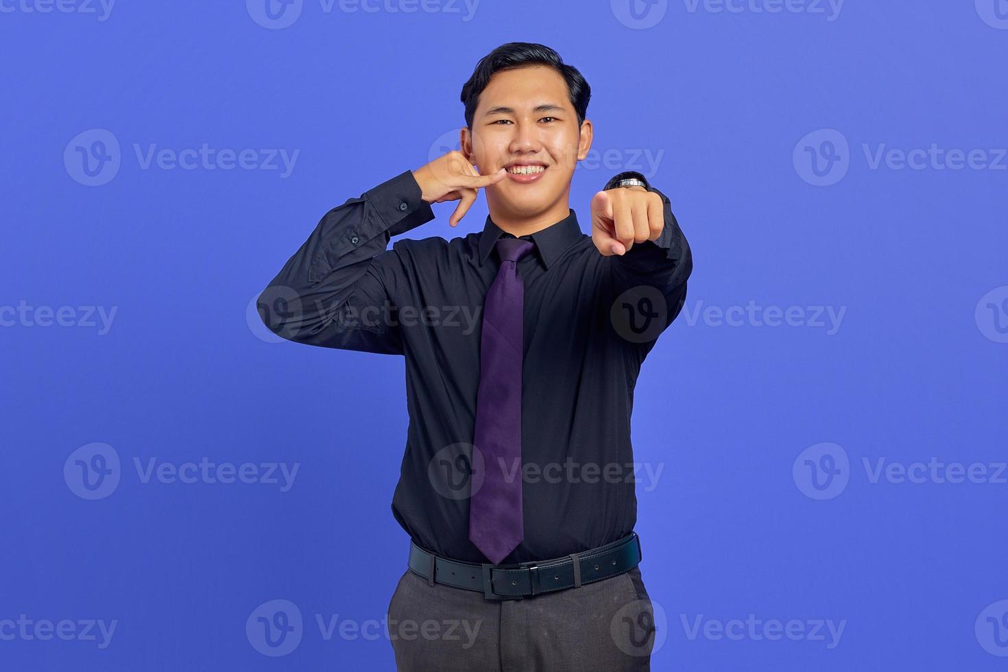 Porträt eines attraktiven asiatischen Mannes machen Rufzeichen und zeigen auf die Kamera über violettem Hintergrund foto