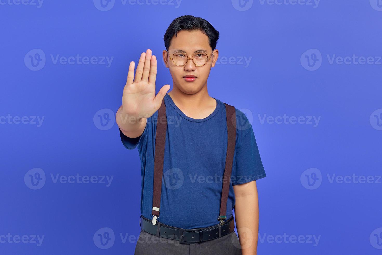 Asiatischer junger Mann, der eine Stoppgeste mit der Handfläche macht, die über lila Hintergrund isoliert ist? foto