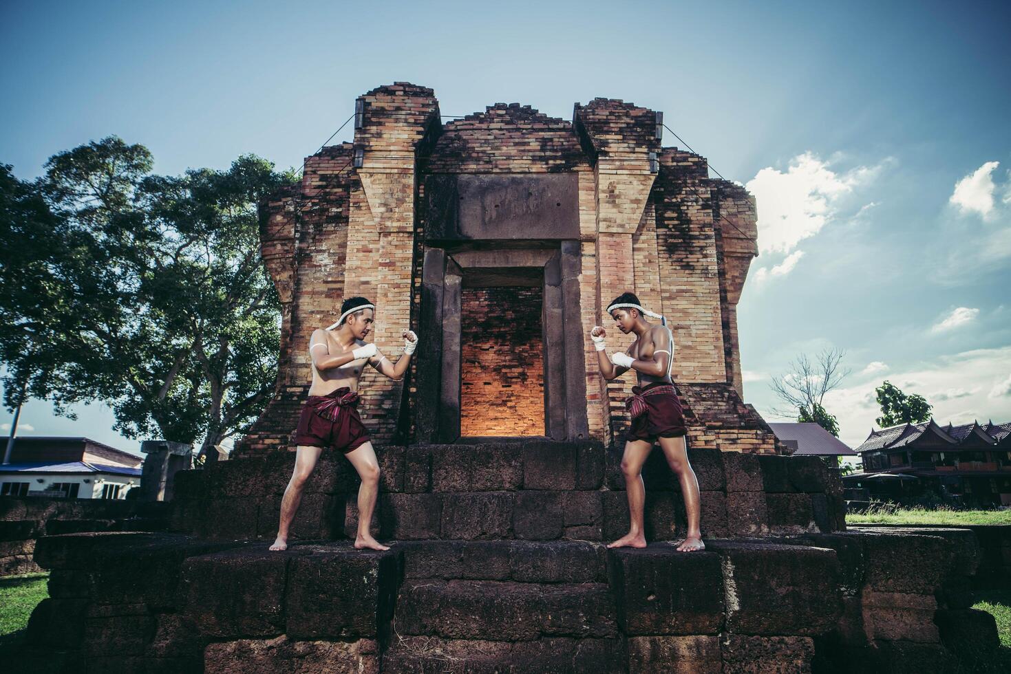 thai-boxer wickeln das band in ihre hände und stellen sich auf den stein vor der tür. foto