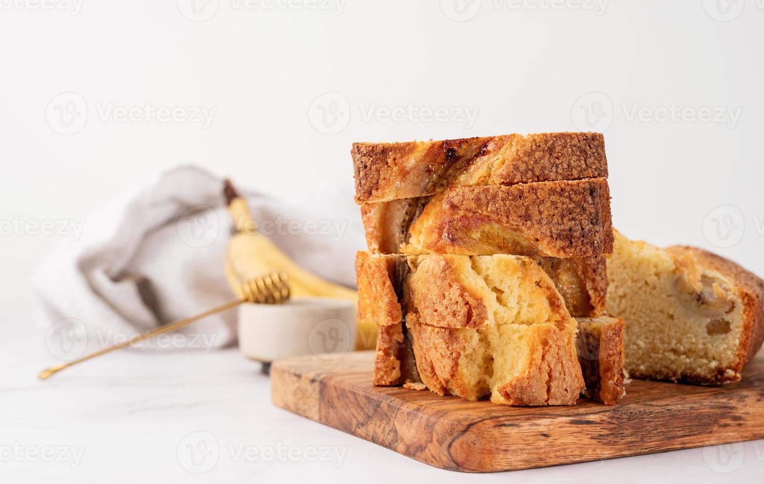 Vorderansicht von geschnittenem Bananenbrot auf hellem Betonhintergrund, gestapelte Kuchenstücke foto