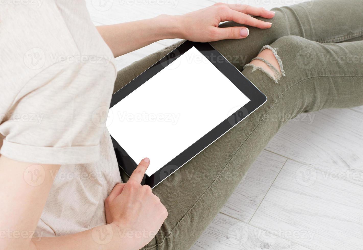 Teenager-Frau Mädchen mit einem Tablet-PC sitzt auf dem Boden in einem Wohnzimmer und berührt den leeren Bildschirm foto