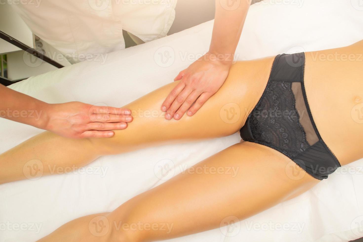 Kosmetikerin praktiziert eine entspannende Oberschenkelmassage im Schönheitsstudio foto