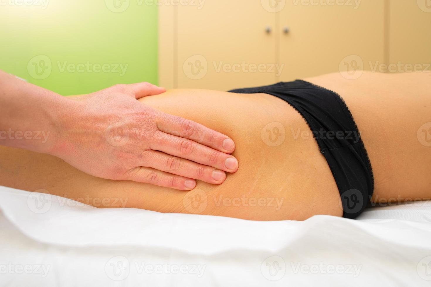 Kosmetikerin praktiziert eine entspannende Oberschenkelmassage foto