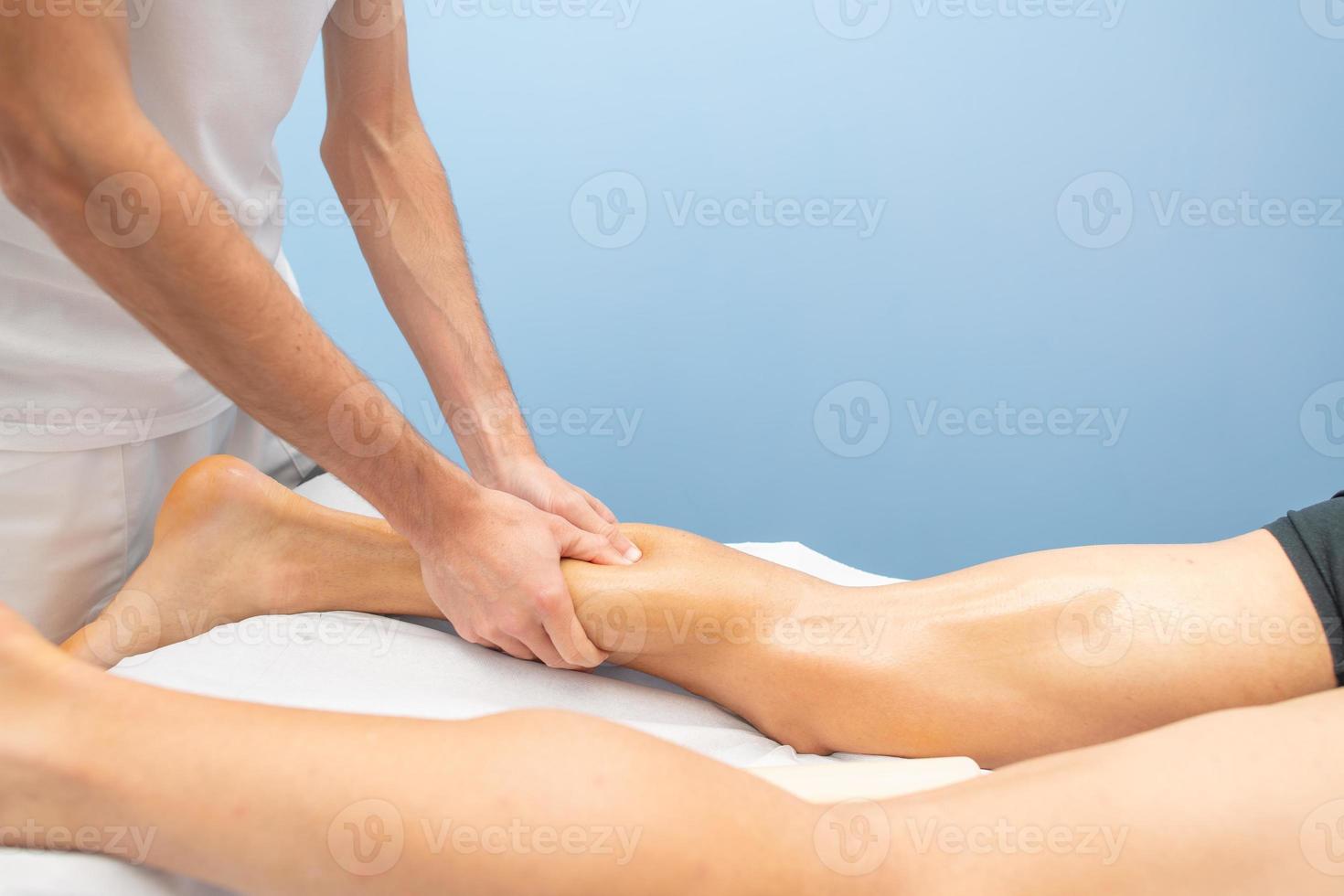 Wadenmassage an einen Sportler durch einen professionellen Physiotherapeuten foto