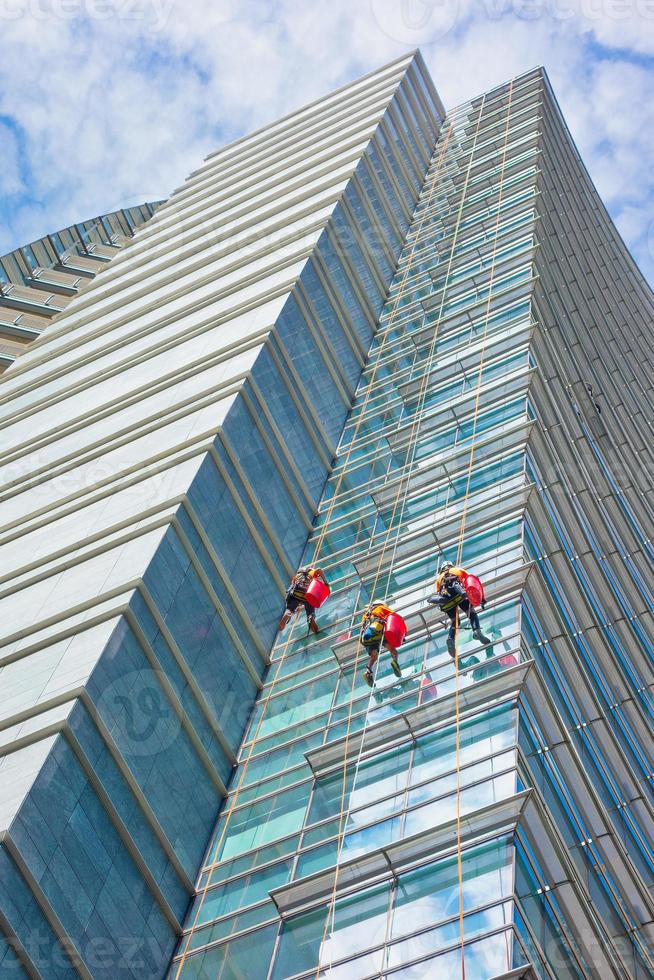 Gruppe von Spezialisten Reinigung der Glasfassade eines Wolkenkratzers, Arbeiten mit hohem Risiko foto