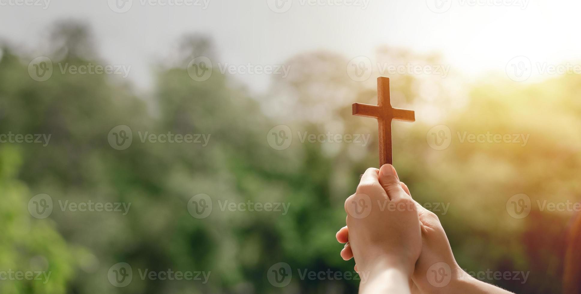 Mädchen, das ein Kreuz hält, um Gott sei Dank zu beten, lobt den Herrn mit Hintergrund im Freien, betet, Ostern und gutes Urlaubskonzept foto