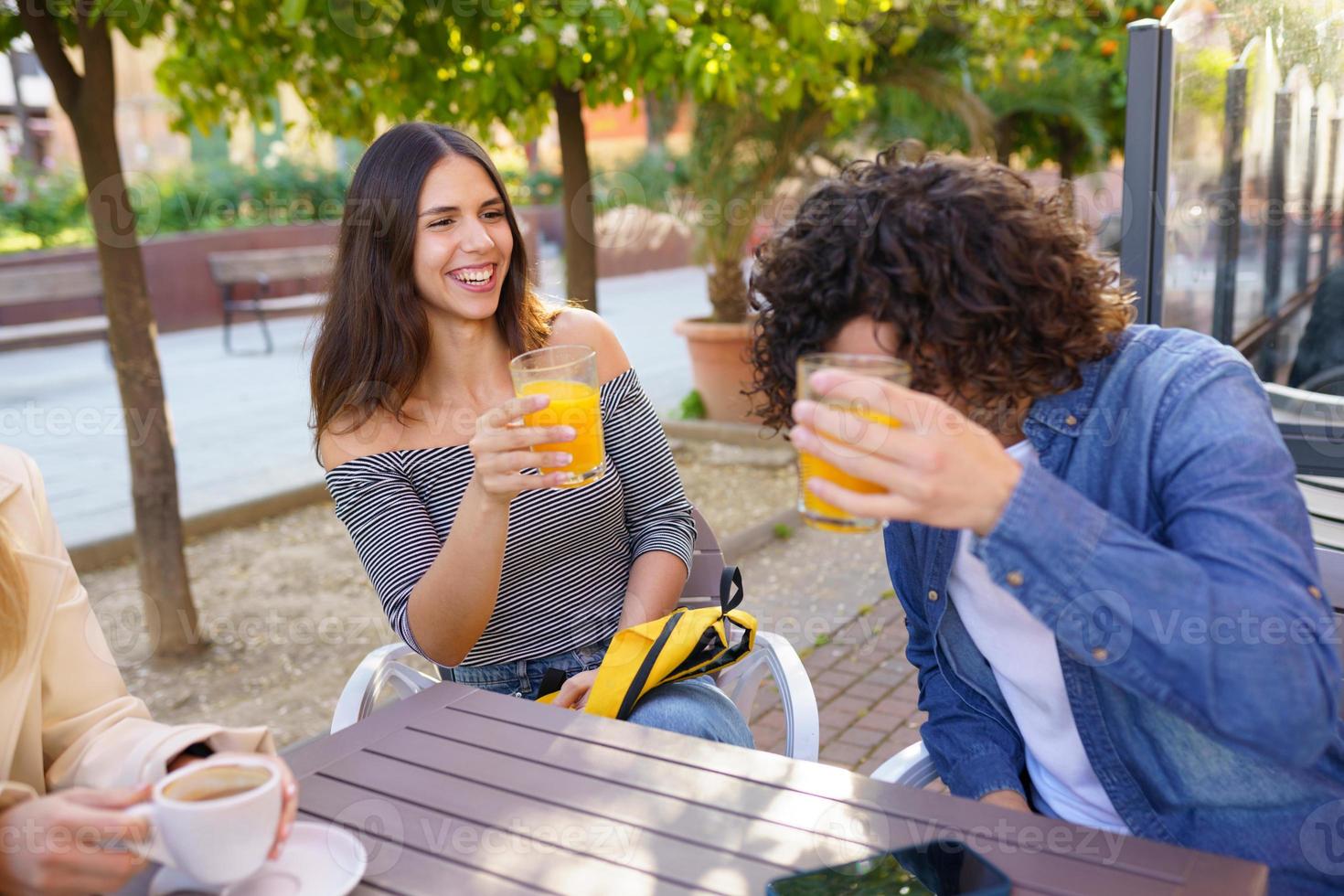 ein paar Freunde, die mit ihrer multiethnischen Gruppe von Freunden bei einem Drink anstoßen foto