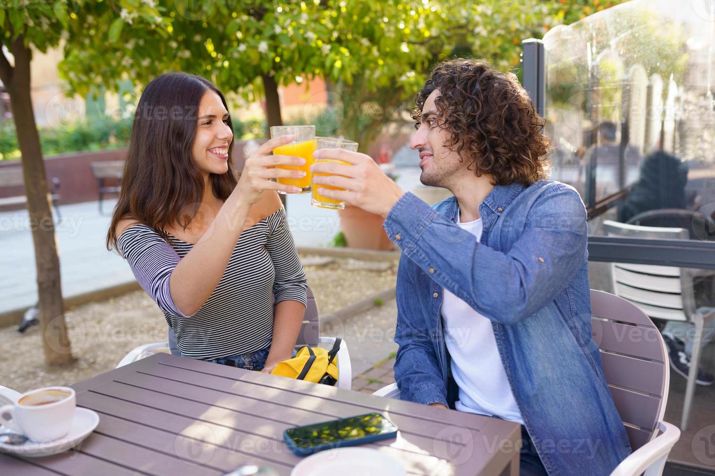 ein paar Freunde, die mit ihrer multiethnischen Gruppe von Freunden bei einem Drink anstoßen foto