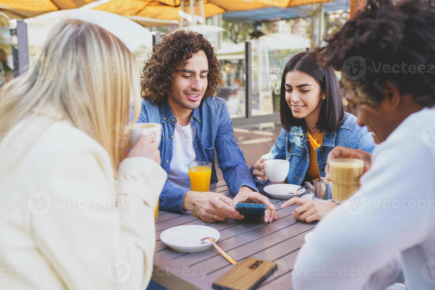 multiethnische Studentengruppe bei einem Drink auf der Terrasse einer Straßenbar. foto