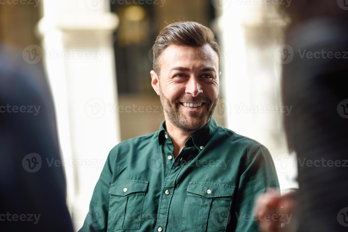 Attraktiver junger Mann, der im Café sitzt und mit Freunden spricht. foto