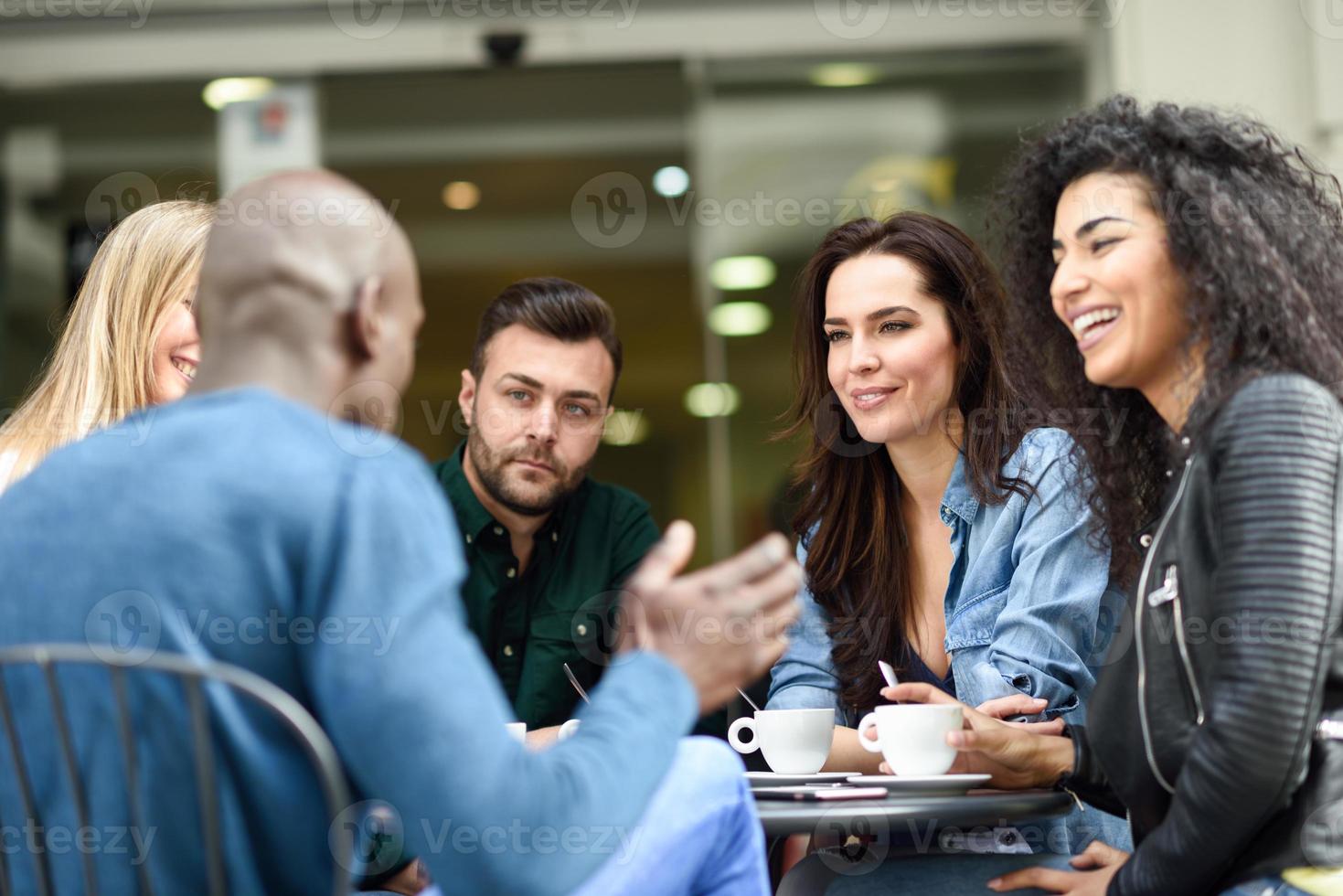 gemischtrassige Gruppe von fünf Freunden, die zusammen einen Kaffee trinken foto