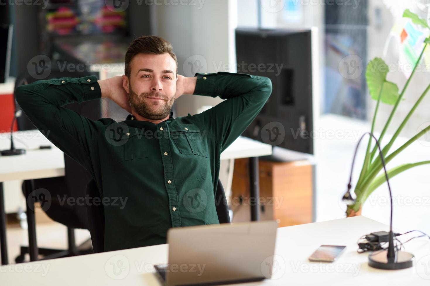 junger Mann, der mit Laptop-Computer auf weißem Schreibtisch studiert. foto