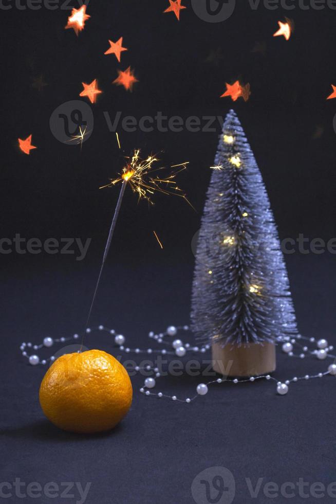 Mandarine, Weihnachtsbaum und Wunderkerzen auf schwarzem Hintergrund. Banner-Postkarten-Einladungskonzept. mit Kopie space.vertikales Foto