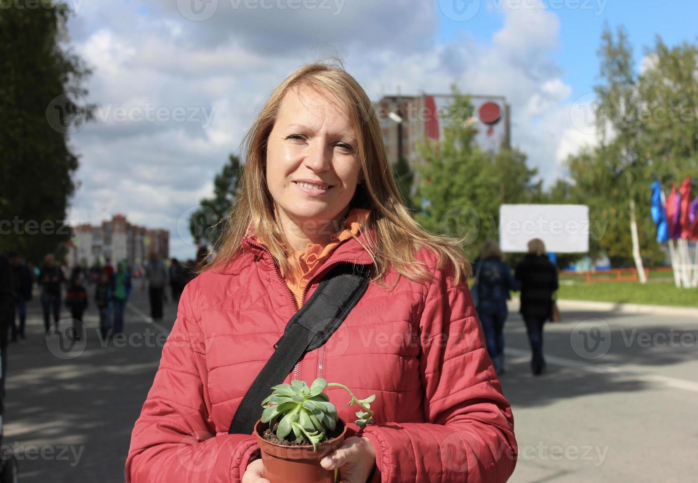 glückliche Frau mittleren Alters, die Sukkulente in einem Topf hält foto