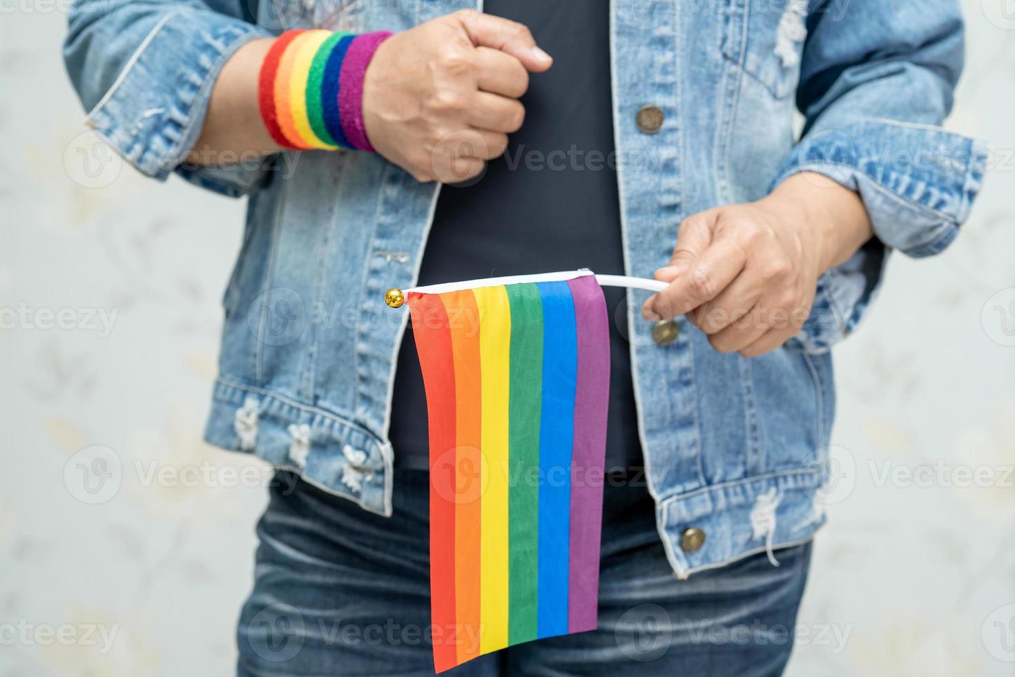 asiatische dame, die blaue jeansjacke oder jeanshemd trägt und regenbogenfarbenfahne hält, symbol des lgbt-stolzmonats, feiert jährlich im juni sozial für schwule, lesbische, bisexuelle, transgender, menschenrechte. foto