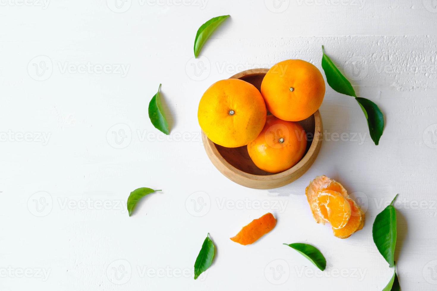 frische Orangenfrüchte in Holzschale auf weißem Hintergrund foto