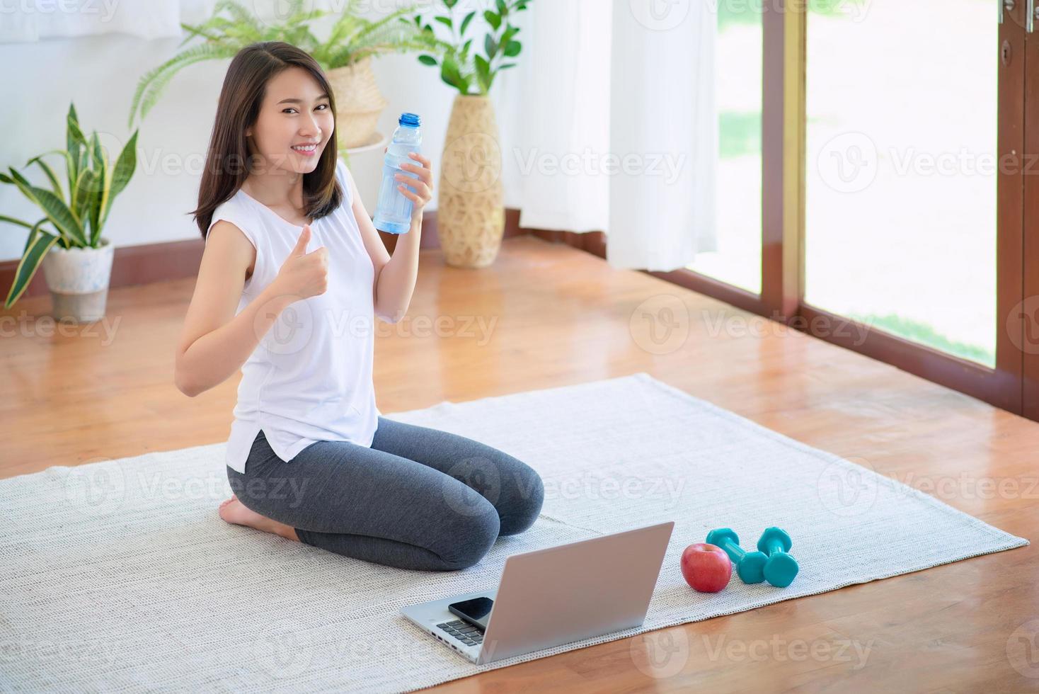 schöne asiatische frau, die fit bleibt, indem sie zu hause für einen gesunden trend-lebensstil trainiert foto