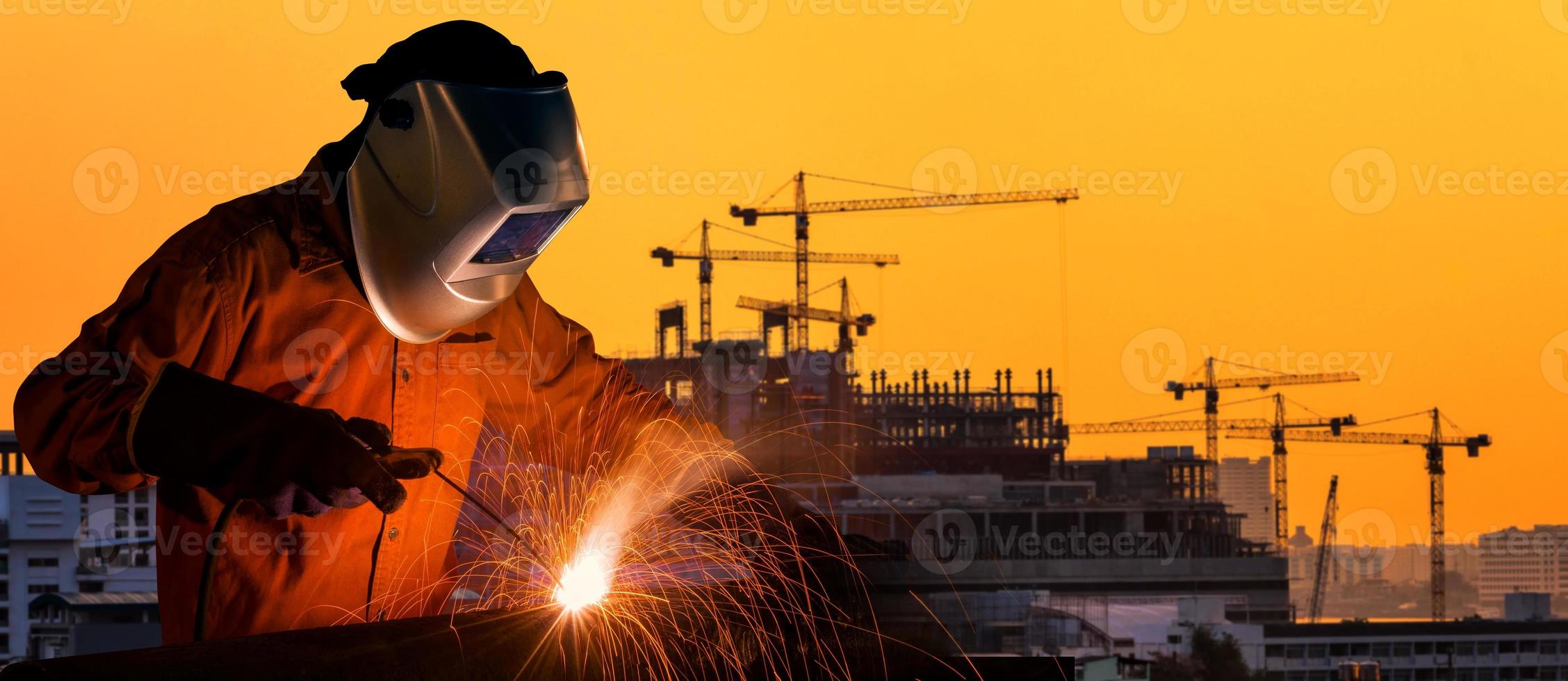 Industriearbeiter Schweißen Stahlkonstruktion für Infrastrukturbauprojekt mit Baustelle im Hintergrund. foto