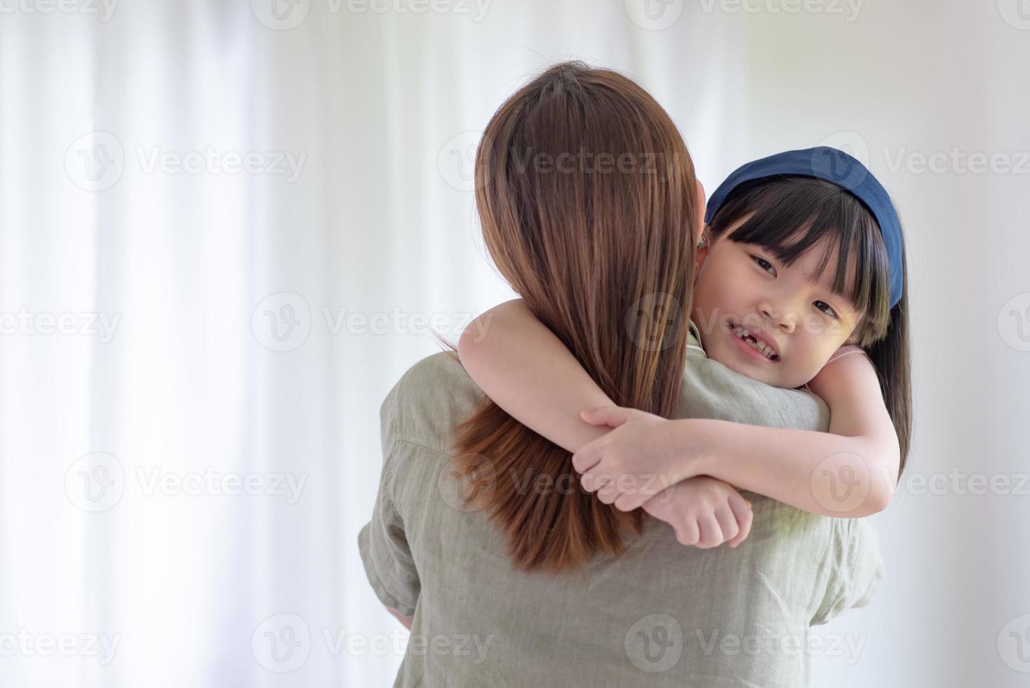 asiatische Mutter macht Liebe mit warmer Umarmung ihrer süßen Tochter zu Hause foto