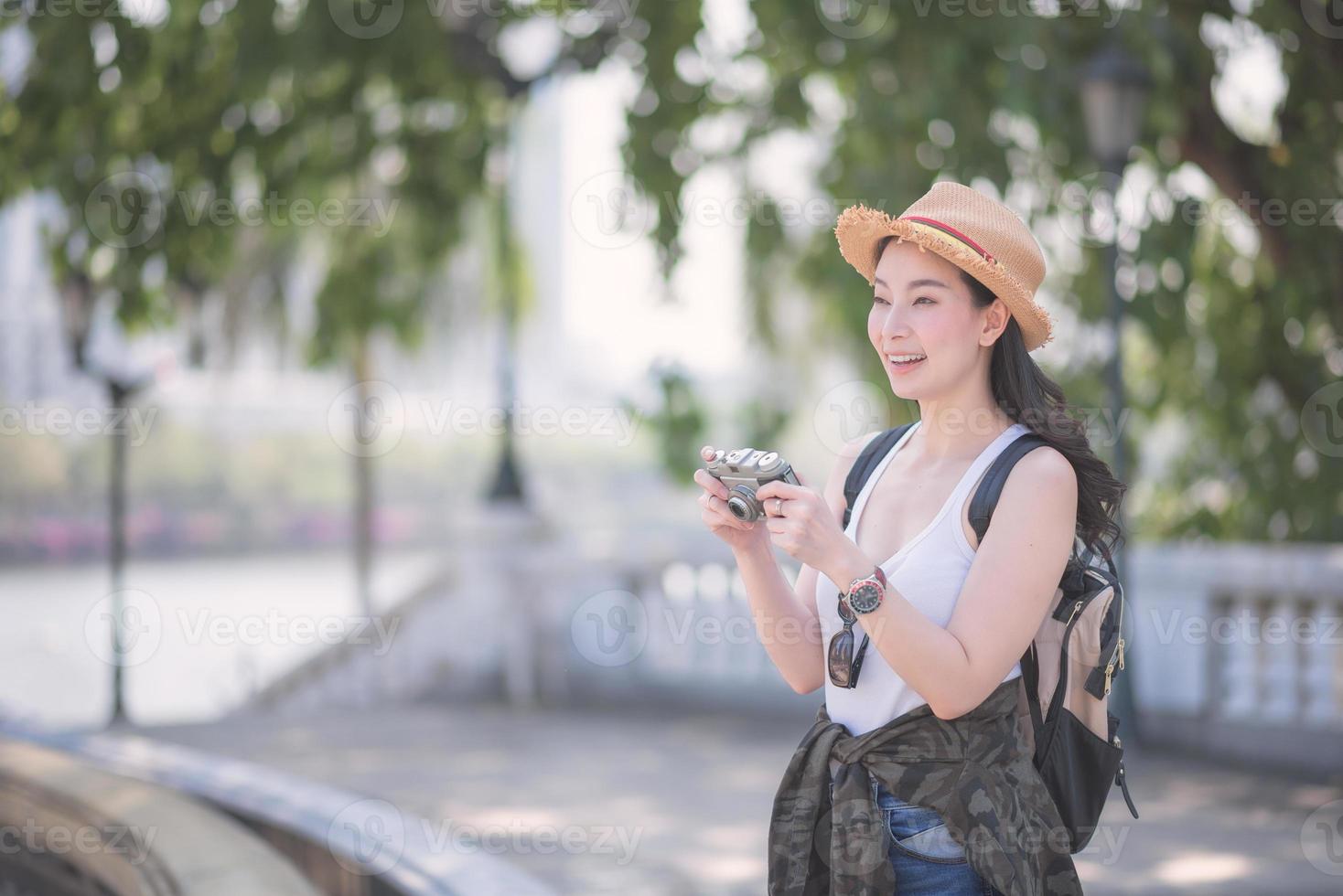 schöne asiatische solo-touristin genießen es, fotos mit retro-kamera an touristischen Sehenswürdigkeiten zu machen. Urlaubsreisen im Sommer.