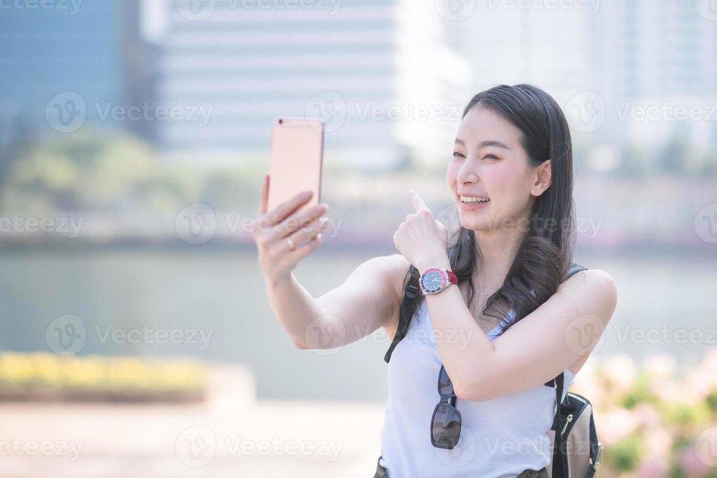 Schöne asiatische Frau genießt die Verwendung der Videoanruftechnologie auf einem Smartphone in der Innenstadt der Stadt. Urlaubsreisen im Sommer. foto