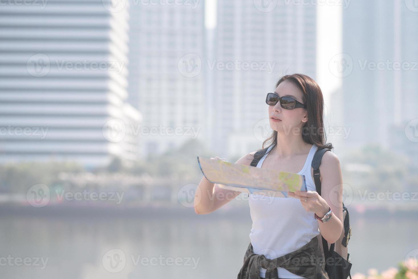 schöne asiatische solo-touristenfrau, die die karte auf der suche nach touristen-Sehenswürdigkeiten betrachtet. Urlaubsreisen im Sommer. foto