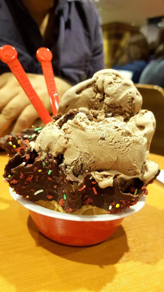 Eiscreme Vanille und Schokoladengeschmack gefrorenes Dessertmuster in Waffelbecher auf Holz. foto