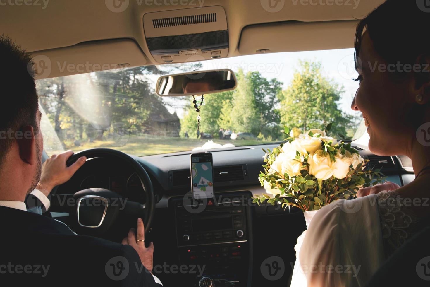 Nahaufnahme Braut und Bräutigam im Auto fahren zur Hochzeitsfeier, um Freunde im Freien zu treffen. Hochzeitspaar feiert Hochzeit in Litauen foto