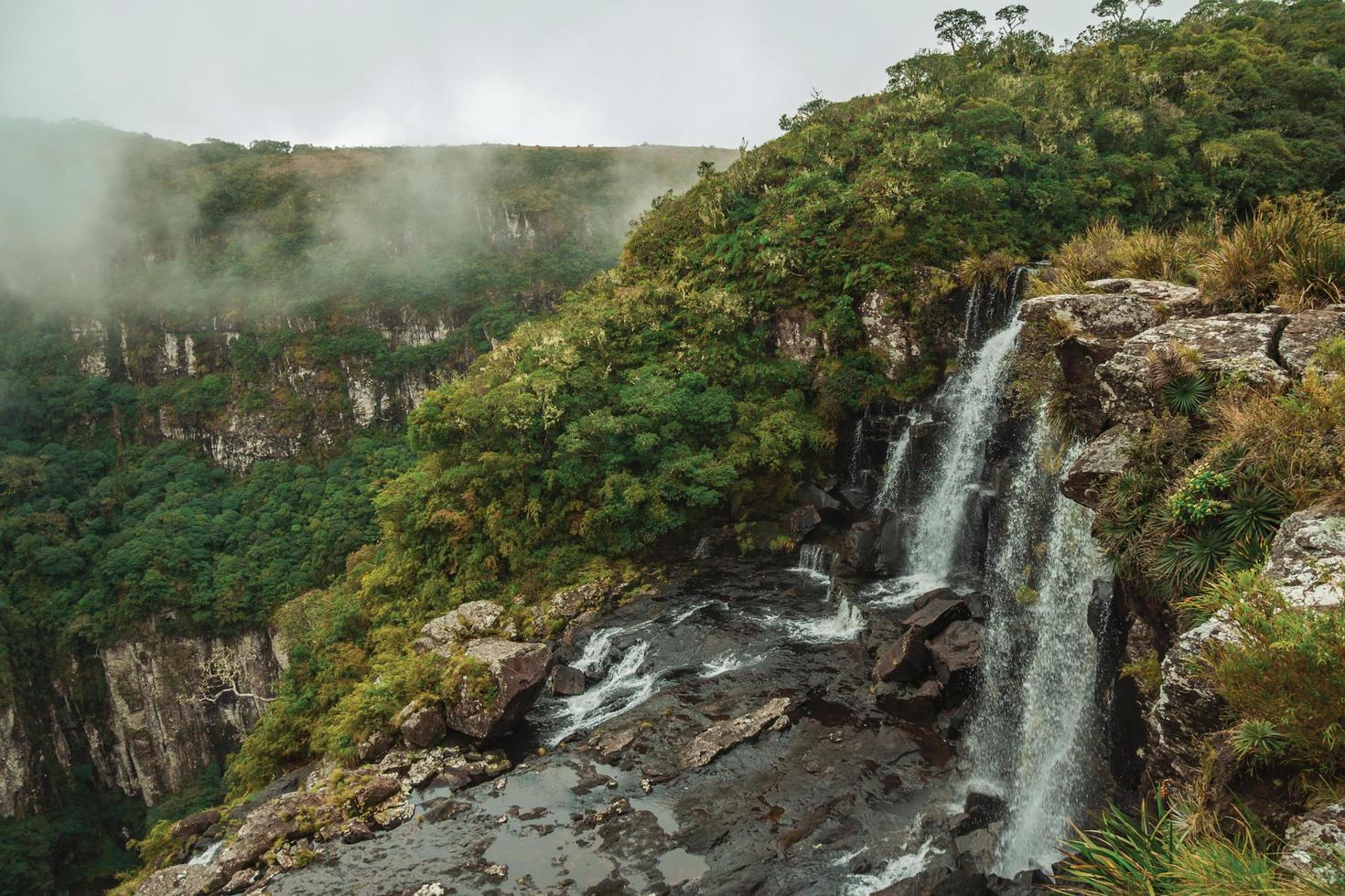 Black Tiger Wasserfall auf einer Klippe aus einem tiefen Tal mit Nebel im Serra Geral Nationalpark in der Nähe von Cambara do Sul. eine kleine landstadt im süden brasiliens mit erstaunlichen natürlichen touristenattraktionen. foto