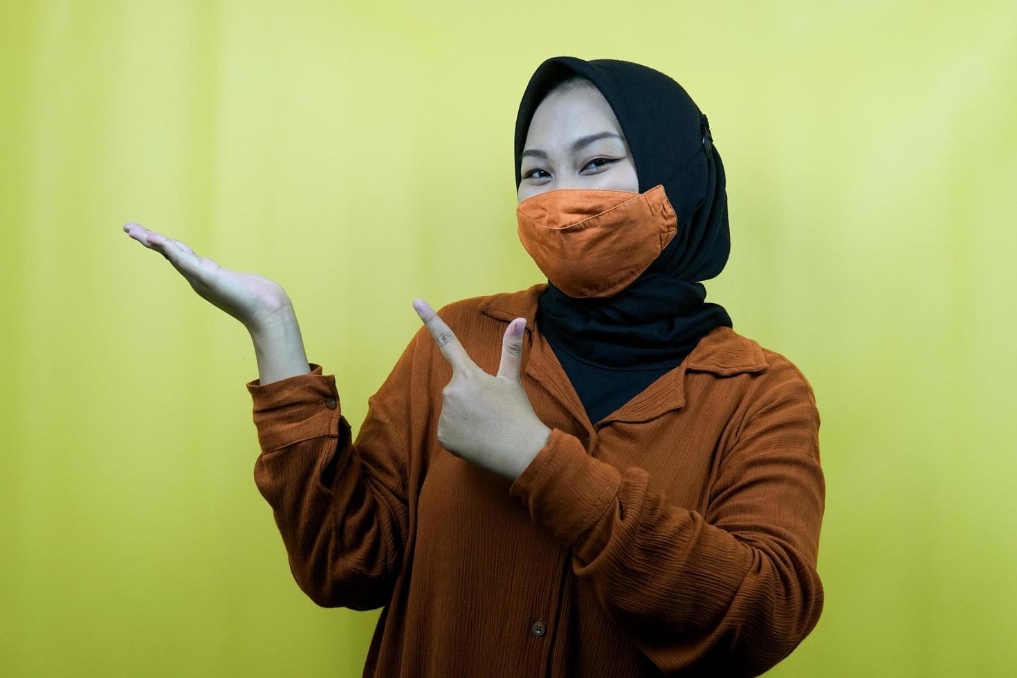 muslimische frau mit maske mit den händen, die auf den leeren raum zeigen, etwas präsentieren, produkt präsentieren, isoliert foto