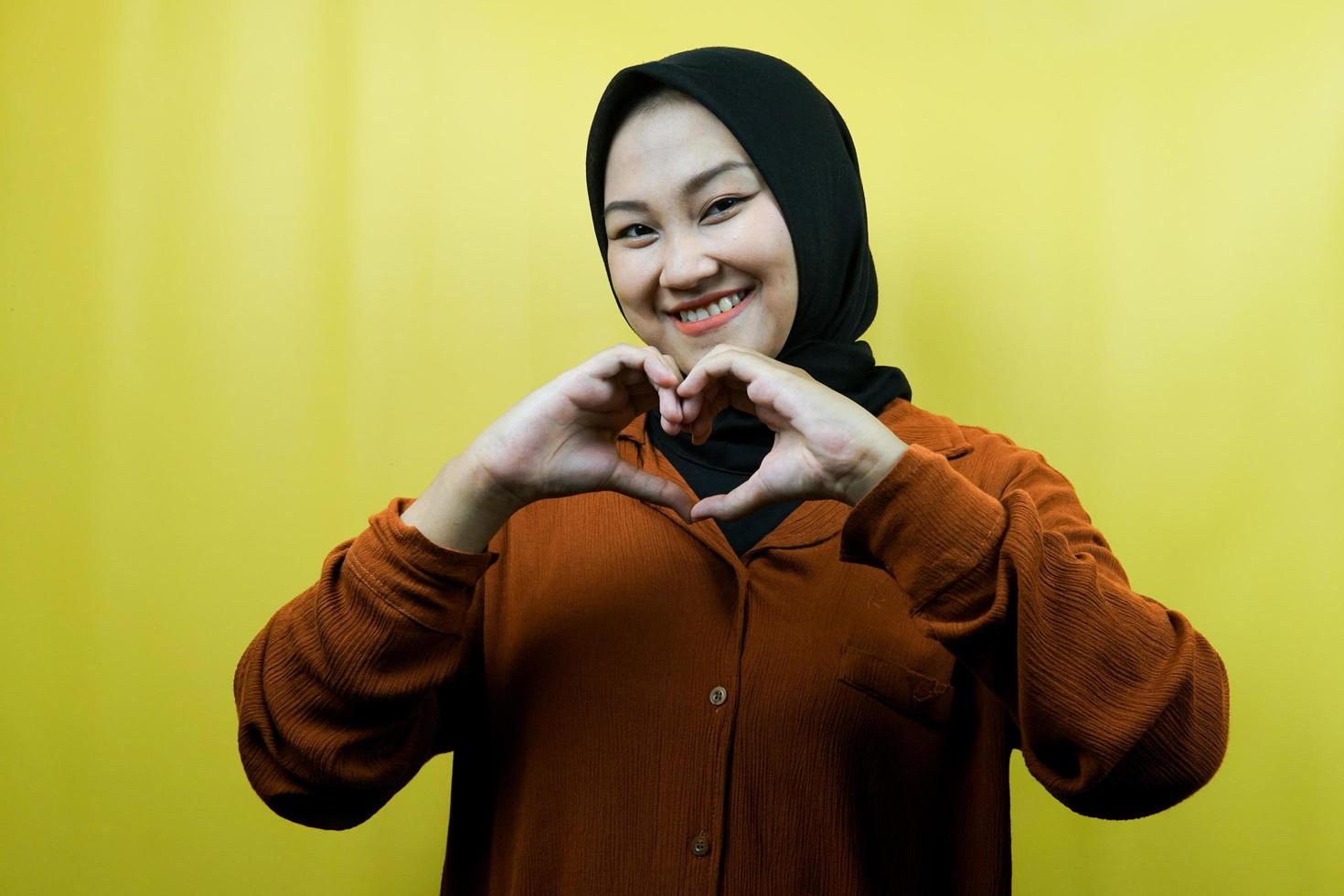 schöne asiatische junge muslimische frau mit händen zeichen der liebe, zuneigung, glücklich, lächelnd selbstbewusst, enthusiastisch und fröhlich, isoliert foto