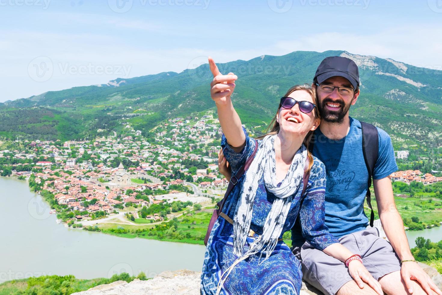 Paar sitzt in der historischen Stätte von Mtskheta und kaukasischer Mann zeigt Finger bis zum Leerzeichen. reise urlaub hintergrund kopieren. foto