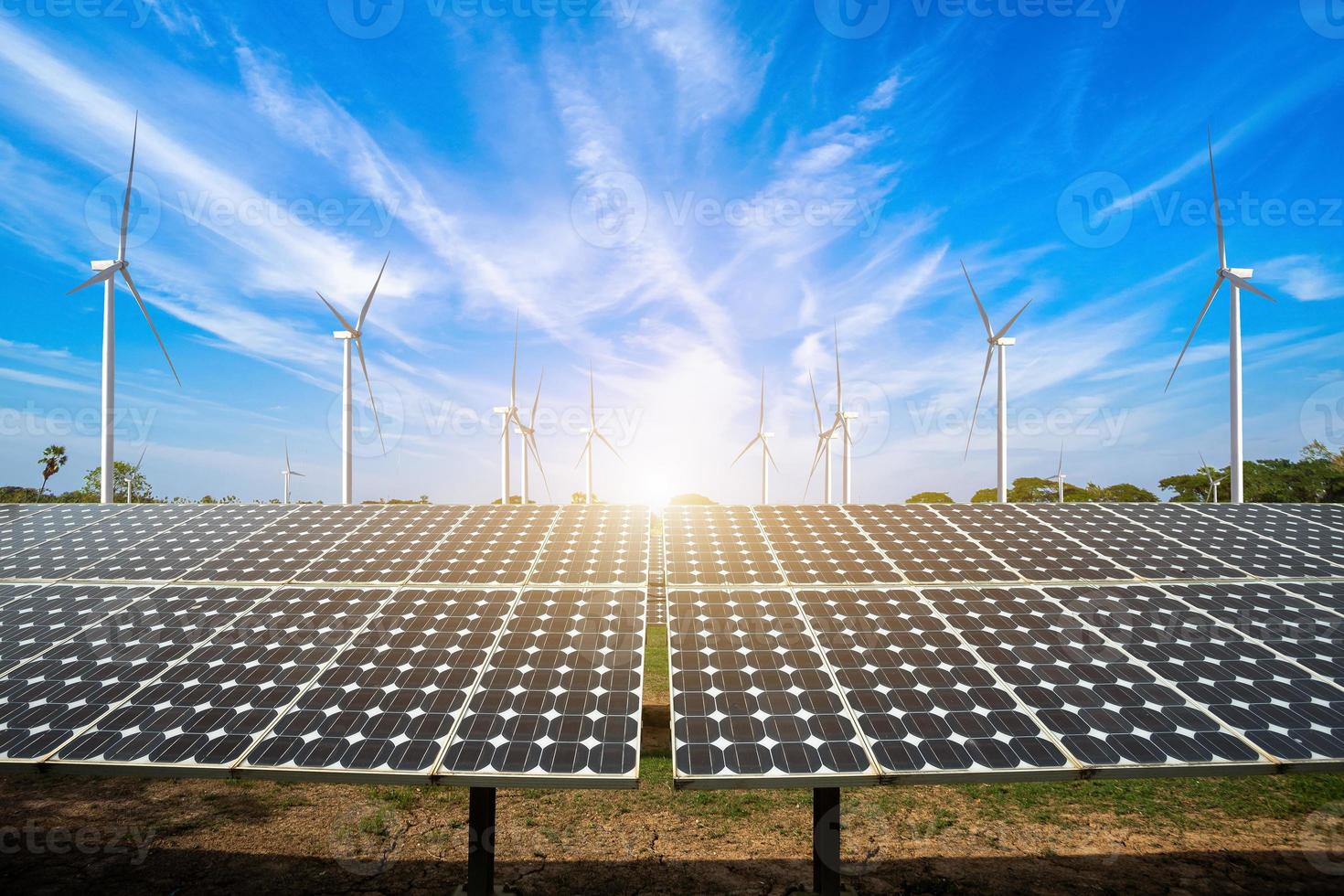 Sonnenkollektoren mit Windkraftanlagen gegen Berglandschaft gegen blauen Himmel mit Wolken, alternatives Energiekonzept, saubere Energie, grüne Energie. foto