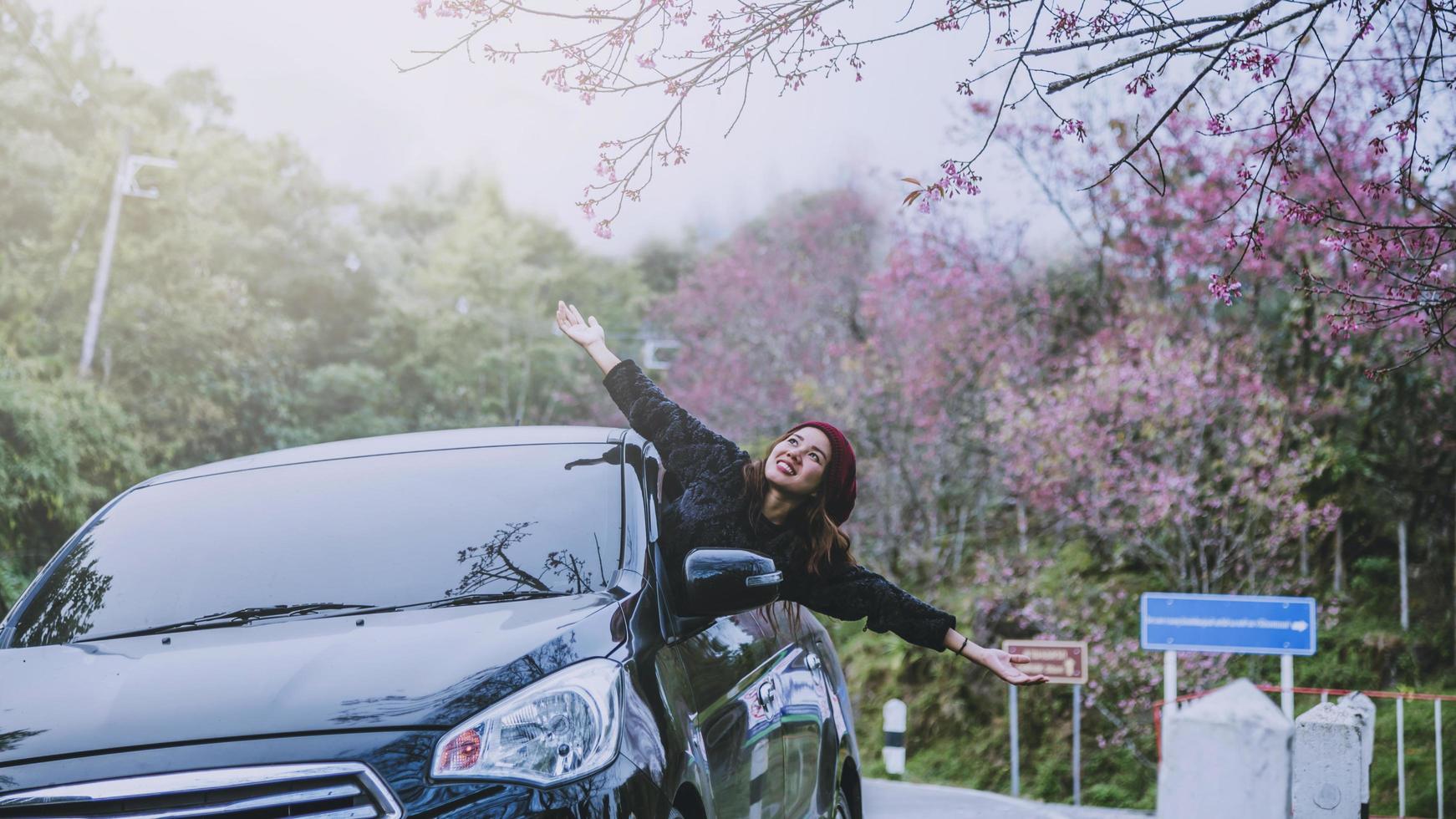 asiatische frauen reisen im urlaub entspannen. mit dem Parkplatz unterwegs. glücklich mit der Natur, rosa Sakura-Blume. im Winter foto