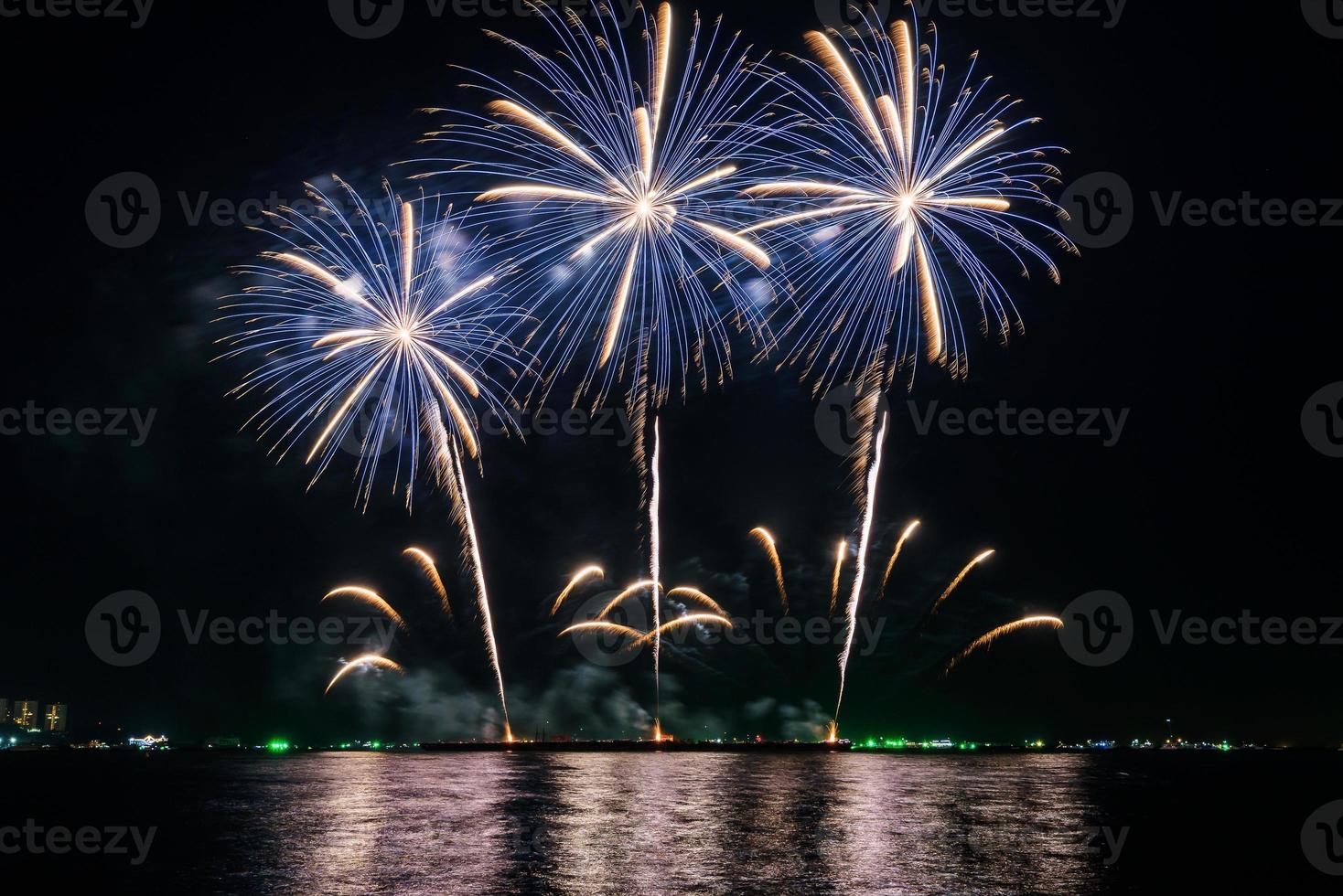 erstaunliches schönes buntes Feuerwerk in der Feiernacht, das am Meeresstrand mit mehrfarbiger Reflexion auf dem Wasser gezeigt wird foto