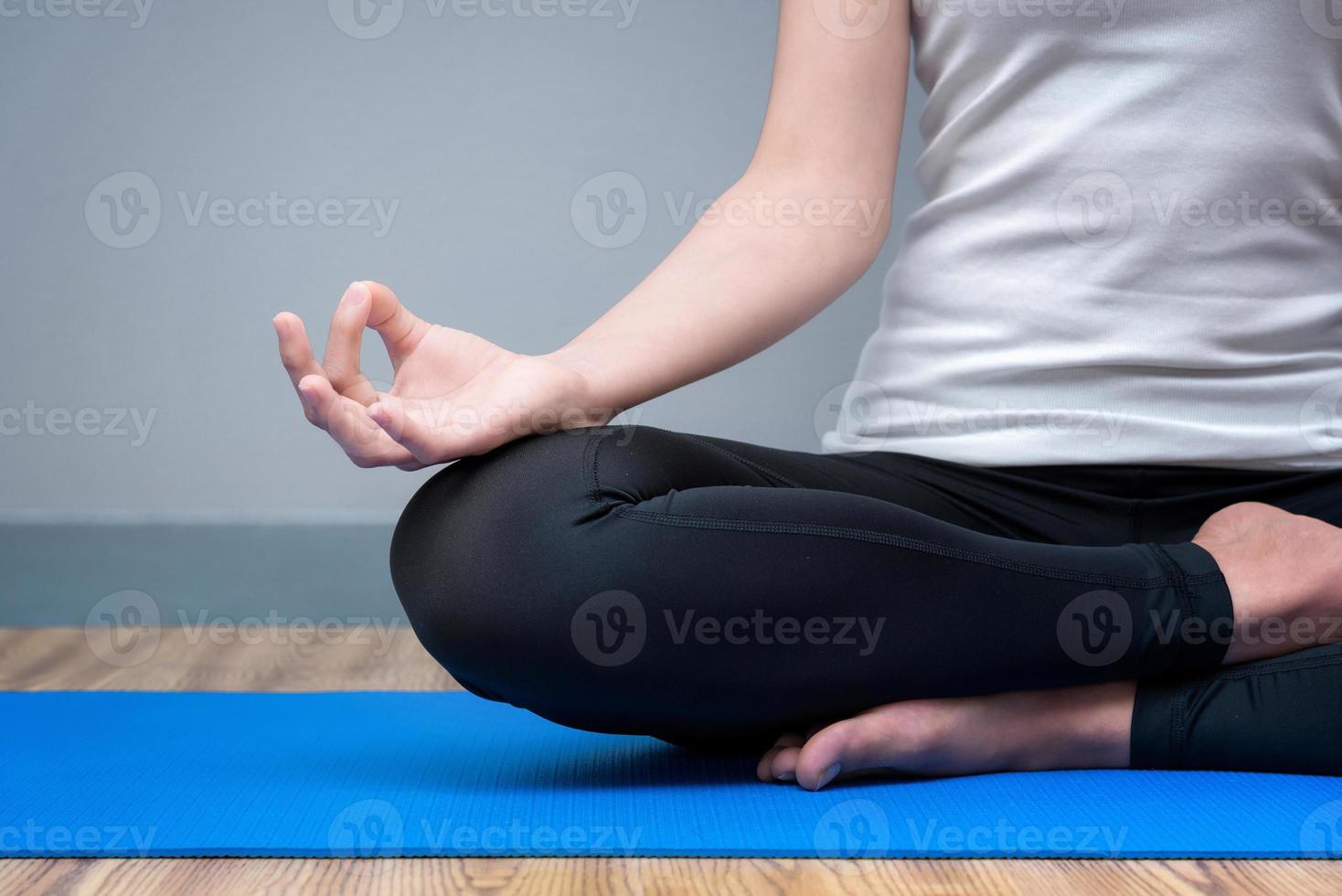 Junge Frau bleibt ruhig und meditiert, während sie Yoga im Yoga-Sport-Fitnessstudio praktiziert. Yoga und Meditation haben gute Vorteile für die Gesundheit. Fotokonzept mit Kopienraum für Yogasport und gesunden Lebensstil. foto