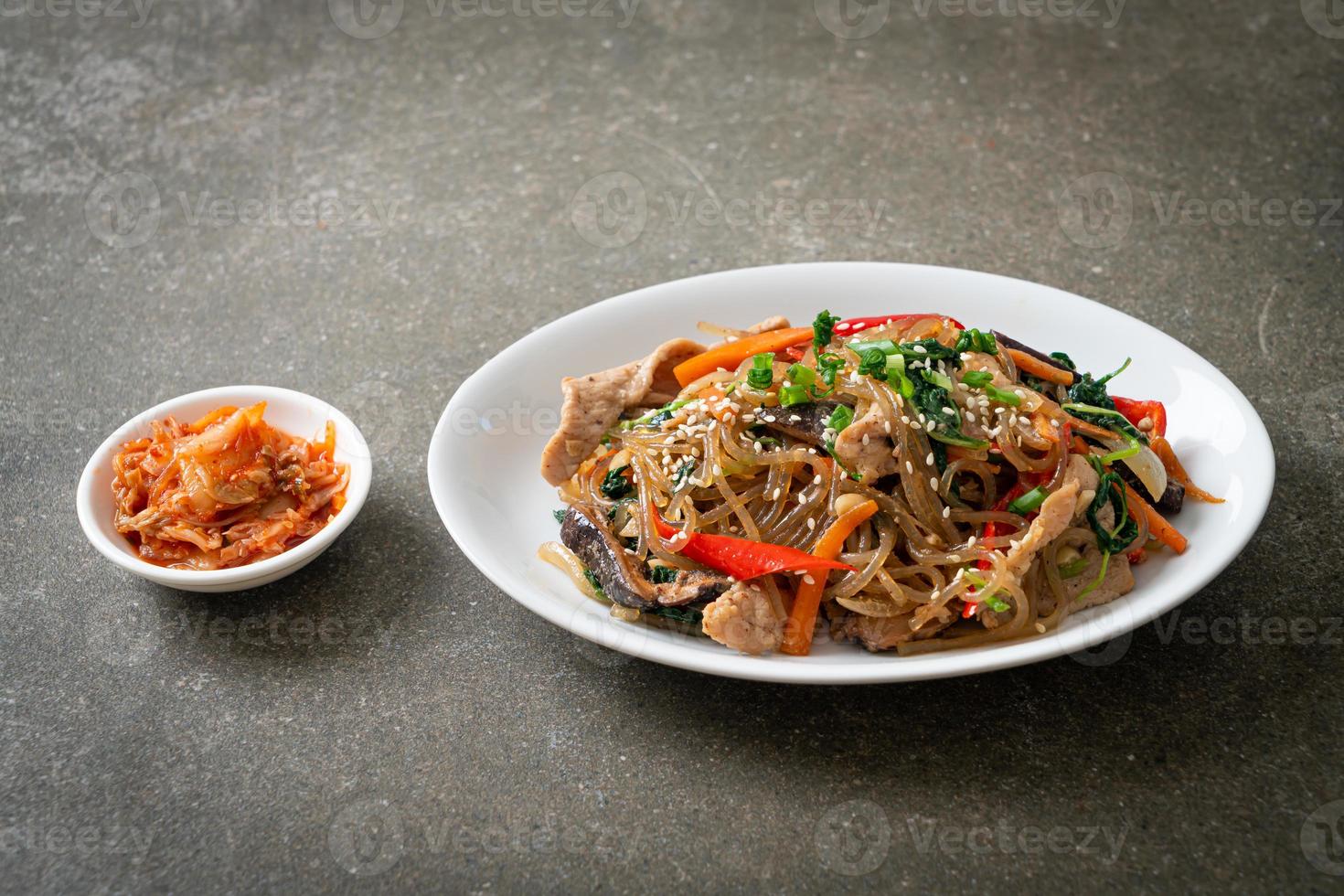 Japchae oder gebratene koreanische Fadennudeln mit Gemüse und Schweinefleisch, garniert mit weißem Sesam foto