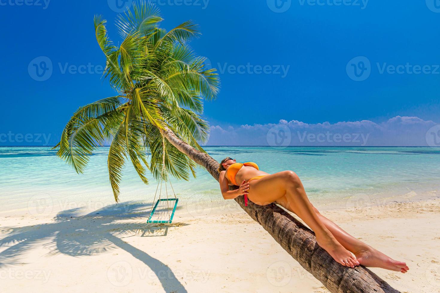 Urlaub am Meer. junge Frau im orangefarbenen Badeanzug am schönen tropischen Strand auf der Palme. foto