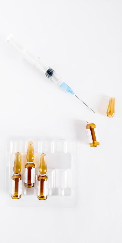 Spritze mit Medizin und Ampullen auf weißem Hintergrund. foto