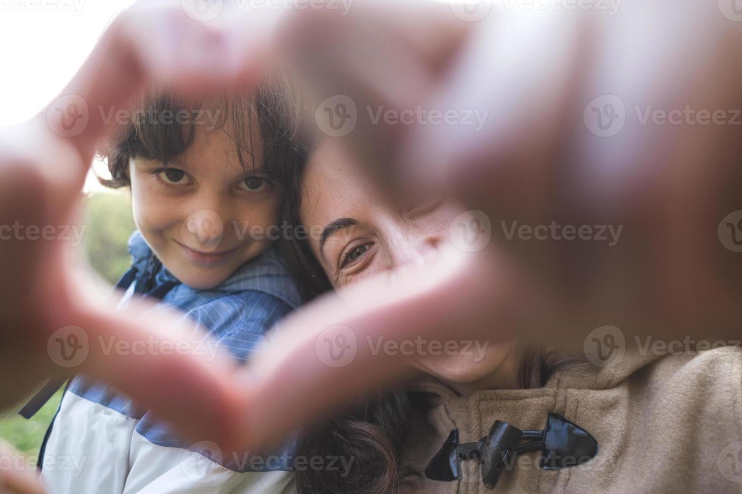 Junge mit Mama gefalteten Fingern in Form eines Herzens. foto