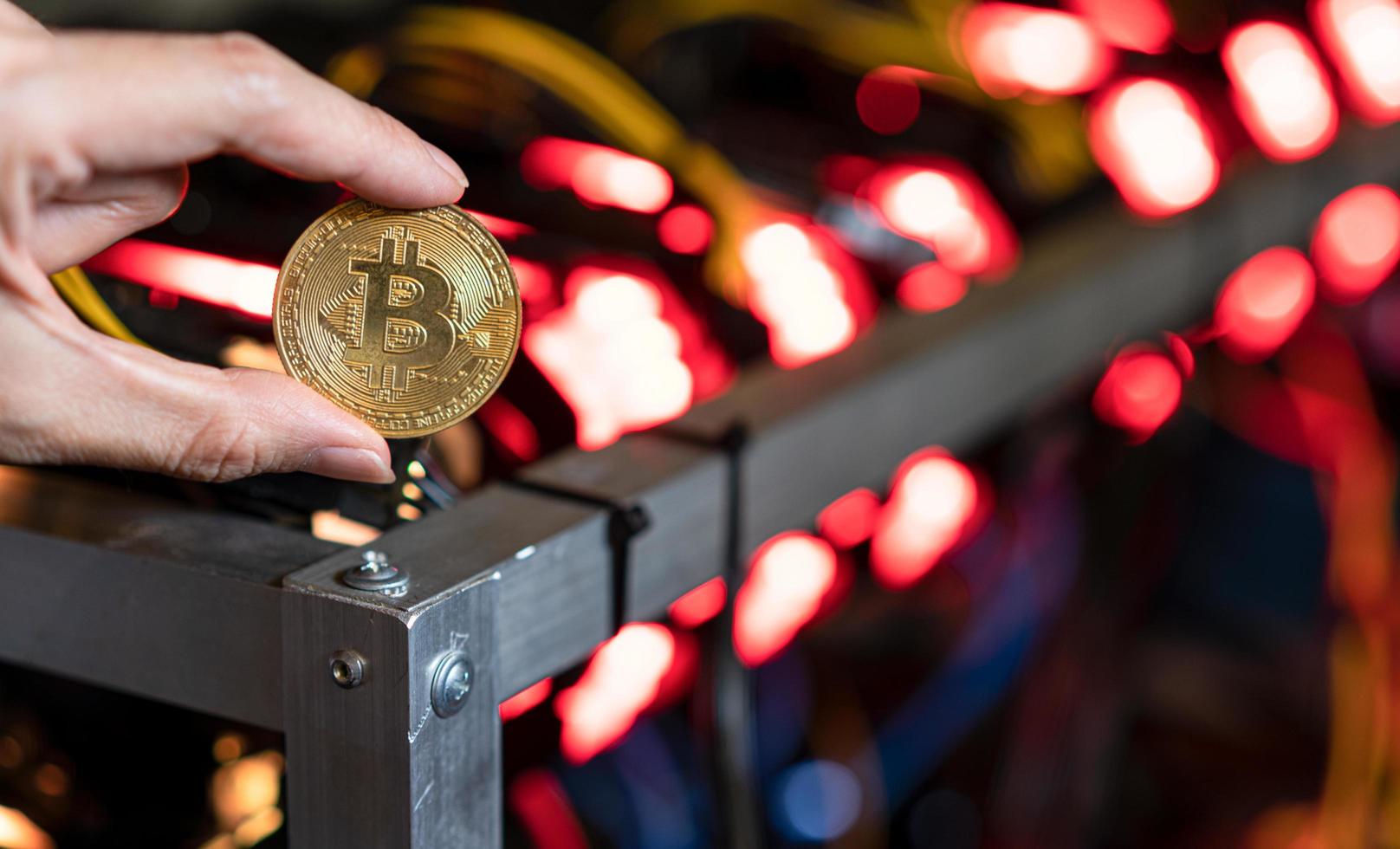 Hand, die Bitcoin auf Bitcoin-Mining-Farm-Hintergrund hält foto